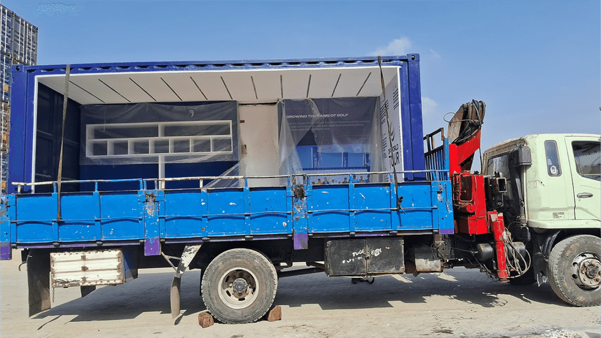 A blue truck with a container on a sunny day.