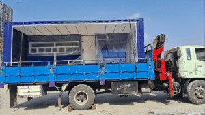 A blue truck with a container on a sunny day.
