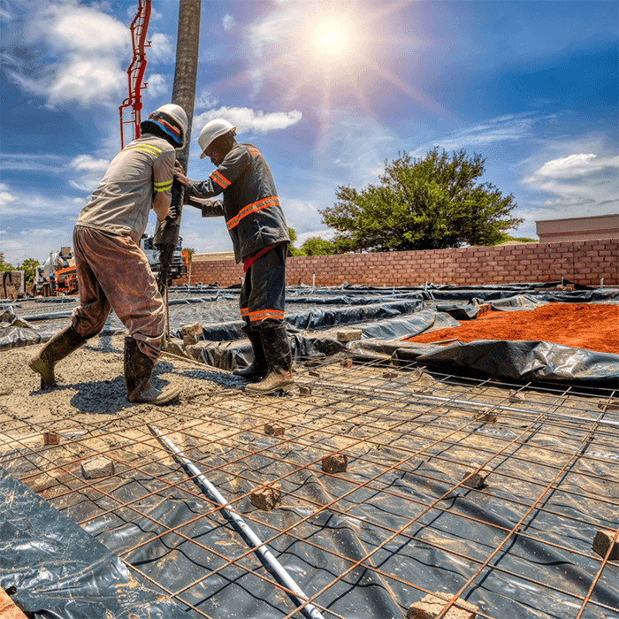 Construction Workers Pouring Concrete Two construction workers pouring concrete at a building site.