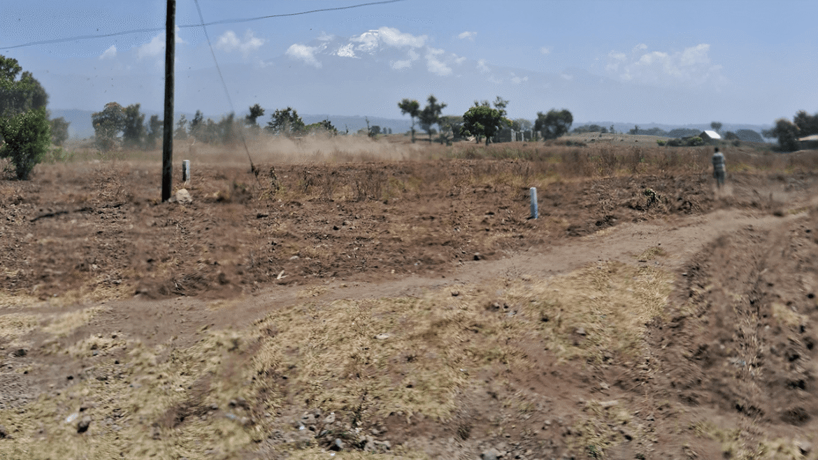 Dusty landscape with a power pole and distant mountains.