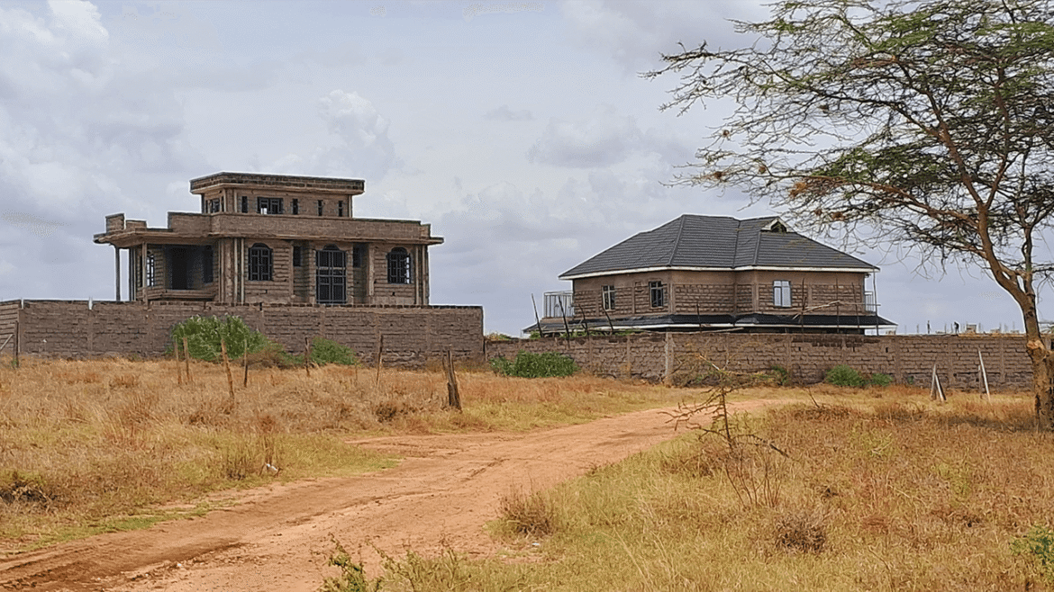 Two houses under construction in a rural landscape.