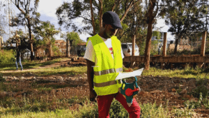 A worker in a yellow reflective vest examining a plan outdoors.