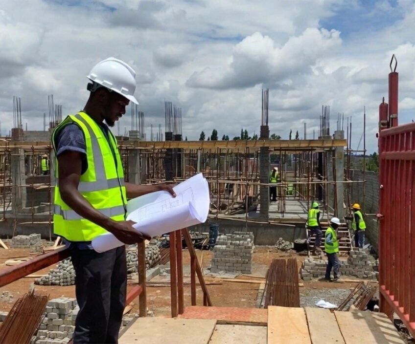 Construction worker reviewing blueprints at a building site.