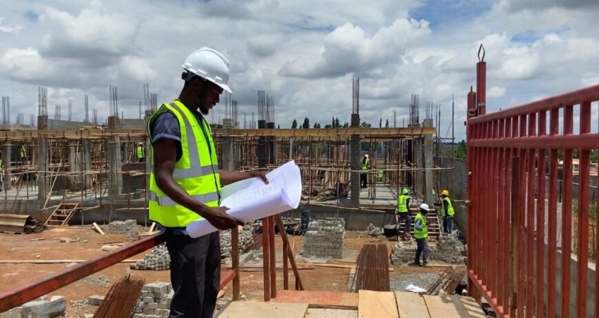 Construction Site Worker Reading Blueprints Construction worker reviewing blueprints at a building site.