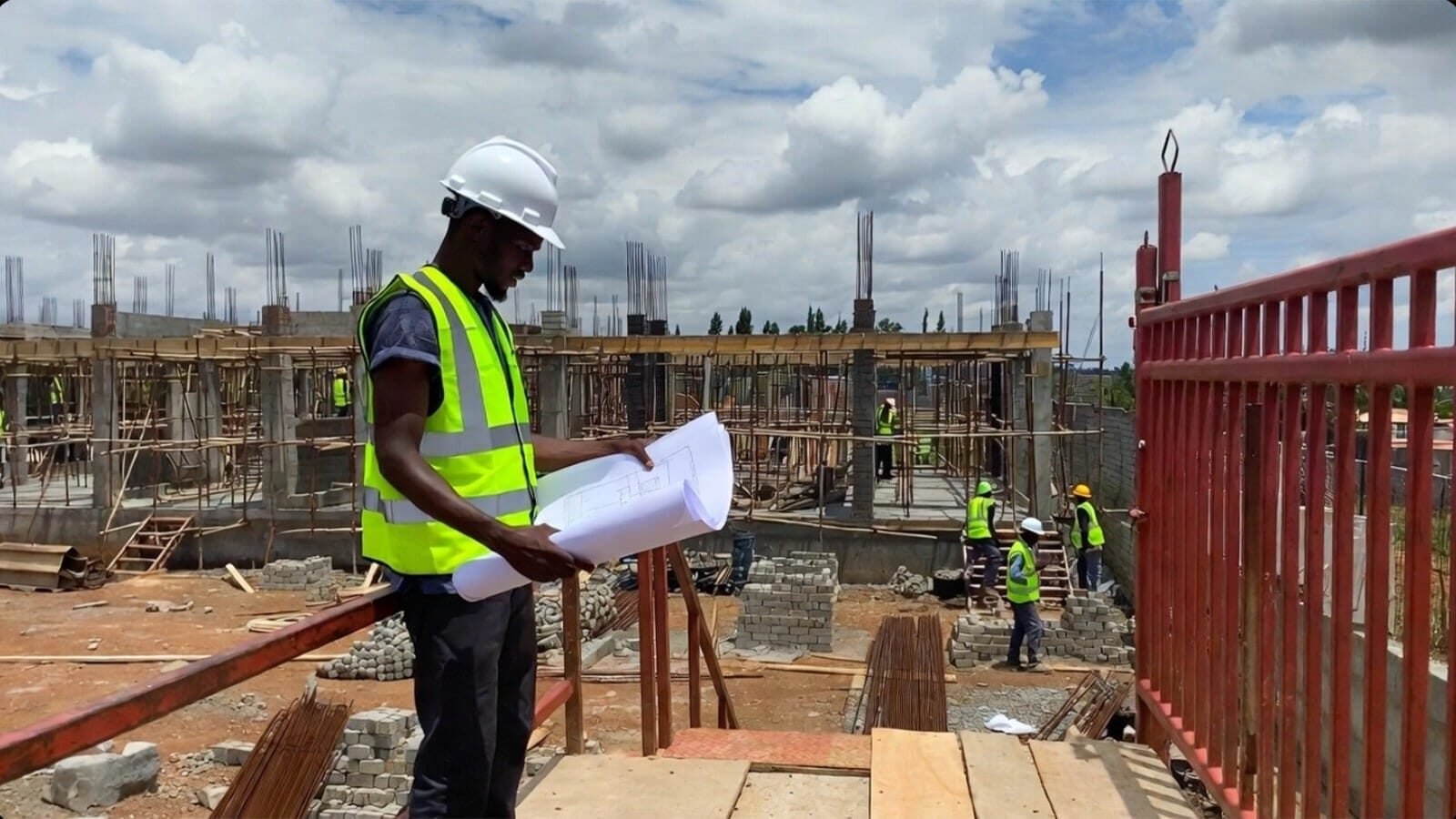 Construction worker reviewing blueprints at a building site.