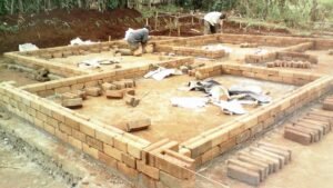 Men working on a brick foundation at a construction site.