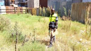 Man in a high-visibility vest standing in tall grass.