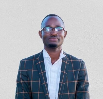 Man With Glasses In Suit Man in a suit with glasses standing against a plain background.