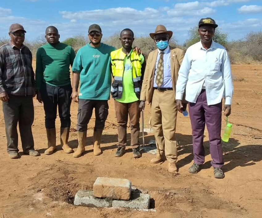 Group of six men at a construction site with a stone.