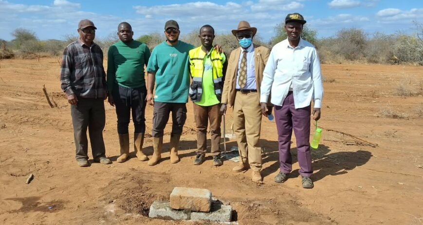 Group of six men at a construction site with a stone.
