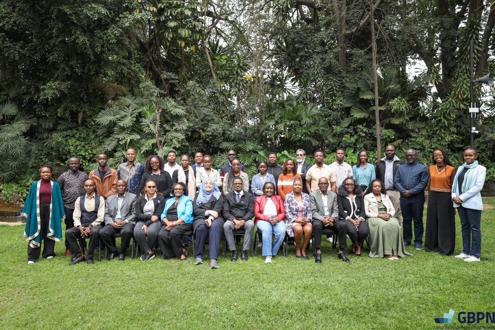 Group photo of diverse individuals in a lush green setting.