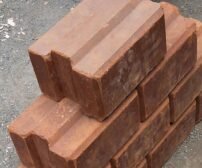 A stack of interlocking soil stabilized blocks on a gravel surface.