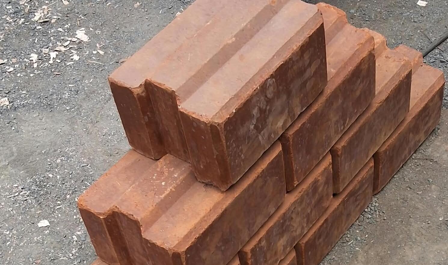A stack of interlocking soil stabilized blocks on a gravel surface.